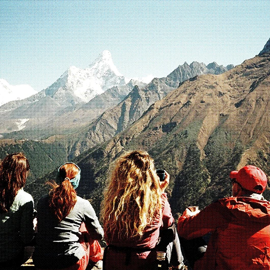 A group of hikers looking out at snow-capped mountain peaks and rugged terrain